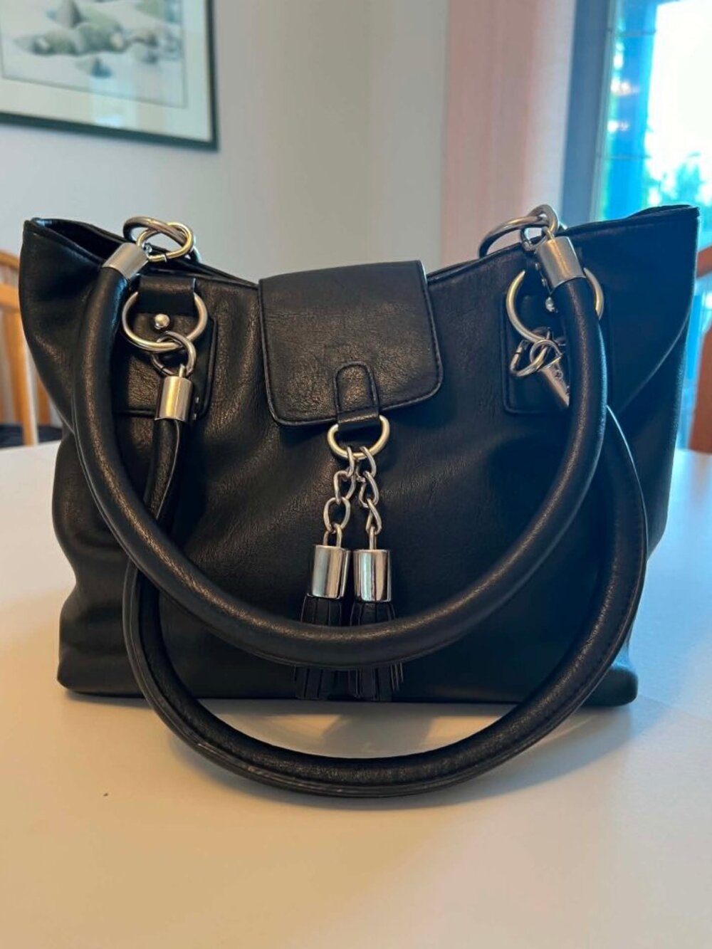 Black faux leather bag with tassel details and chunky silver hardware